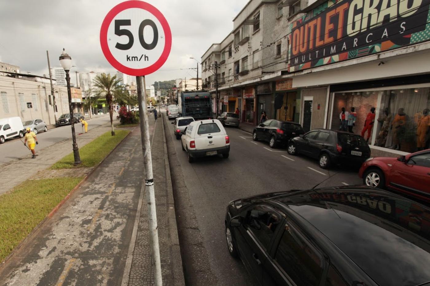 Placa de velocidade de 50km e ao lado via com carros. #paratodosverem