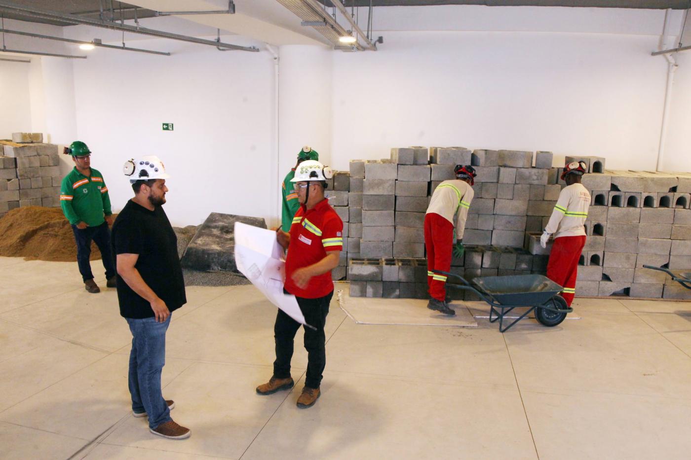 dois homens seguram plangta de construção. #paratodosverem 