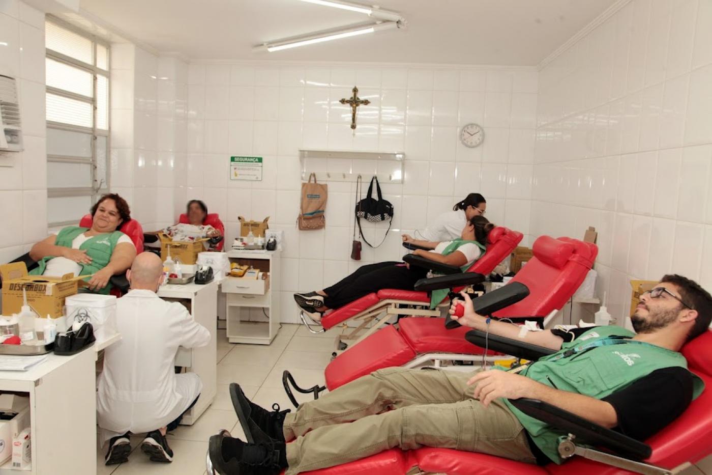 Agentes uniformizados estão sentados em poltronas doando sangue. #paratodosverem 