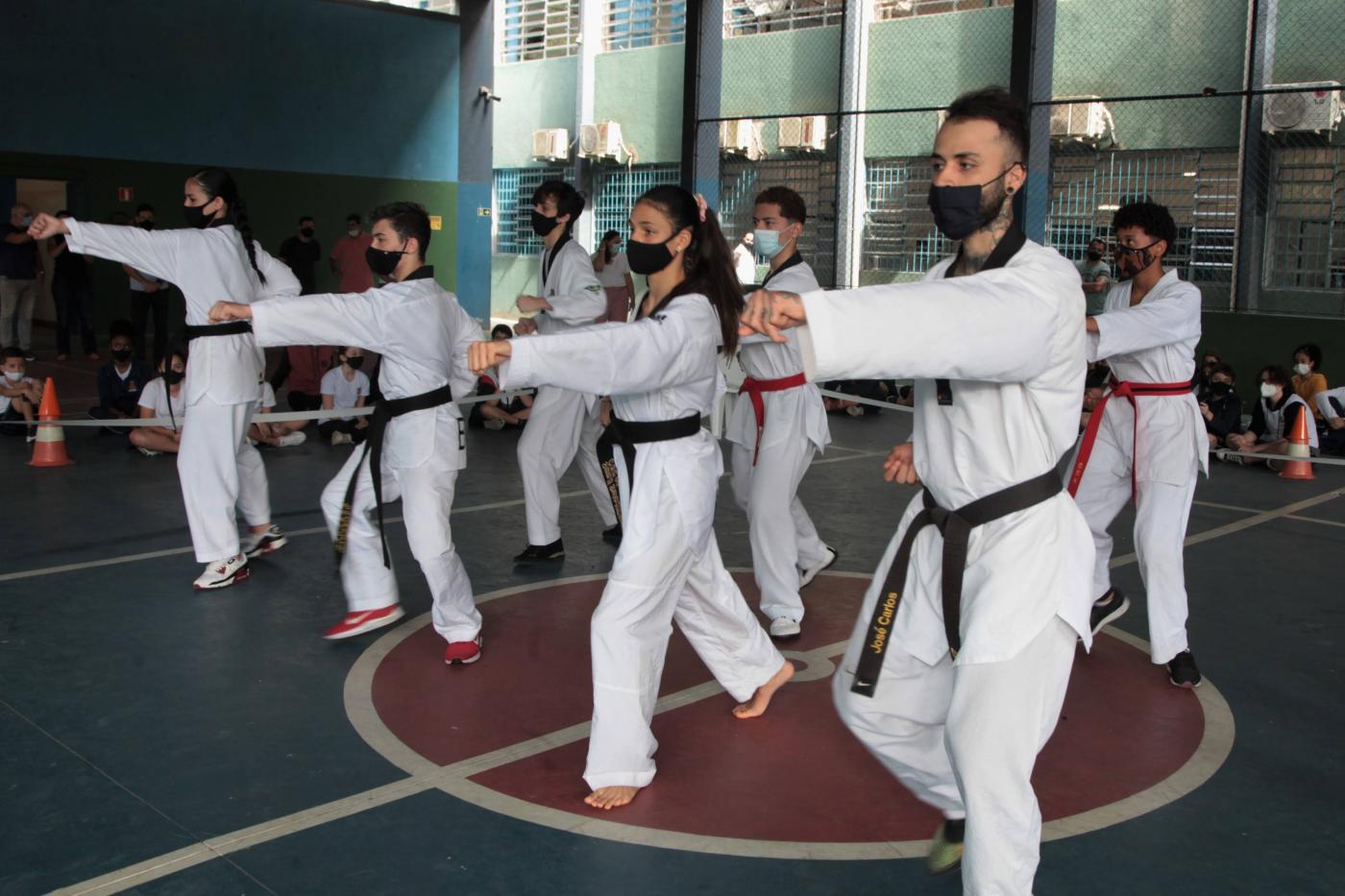 pessoas com uniforme de caratê fazendo exercícios #paratodosverem