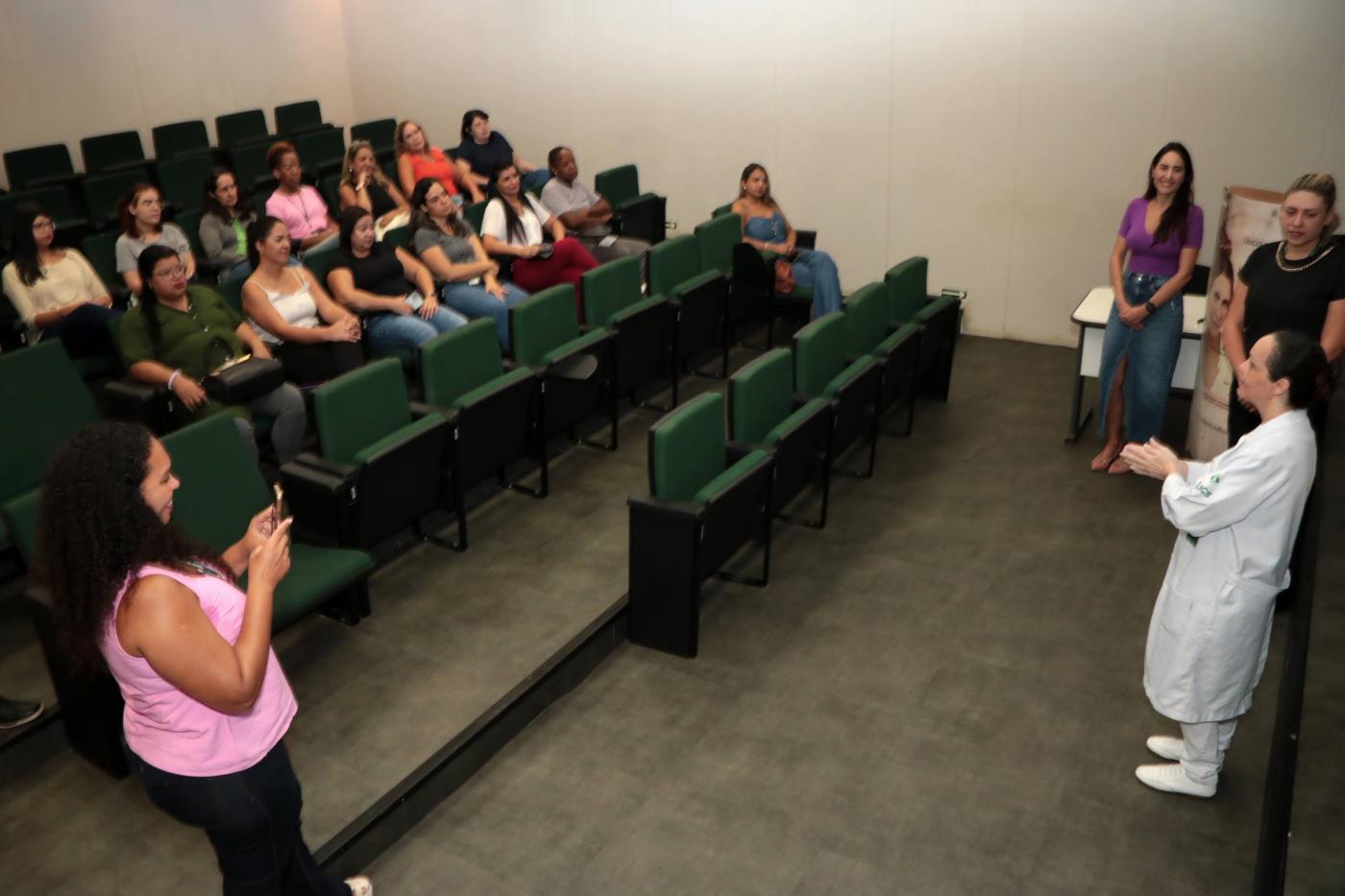 mulheres sentadas em auditório assistem palestra. #paratodosverem 