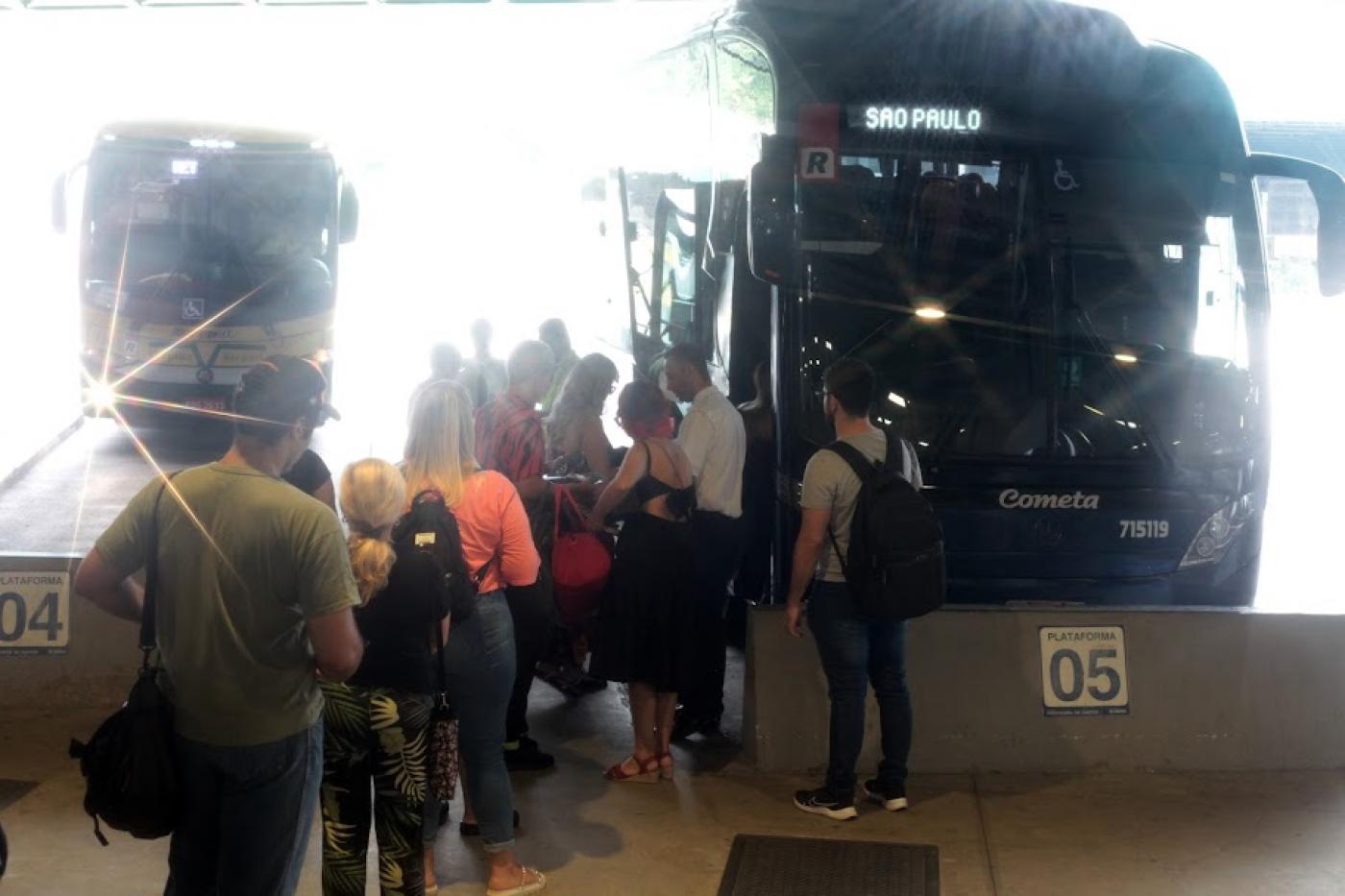 pessoas aguardam para entrar em ônibus parados em baias na rodoviária. #paratodosverem 