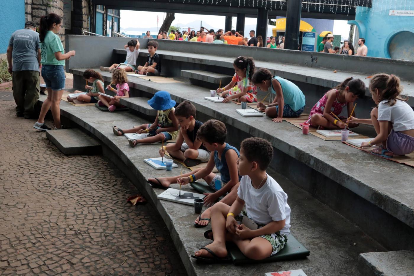 crianças fazem desenhos em área externa do aquário. #paratodosverem