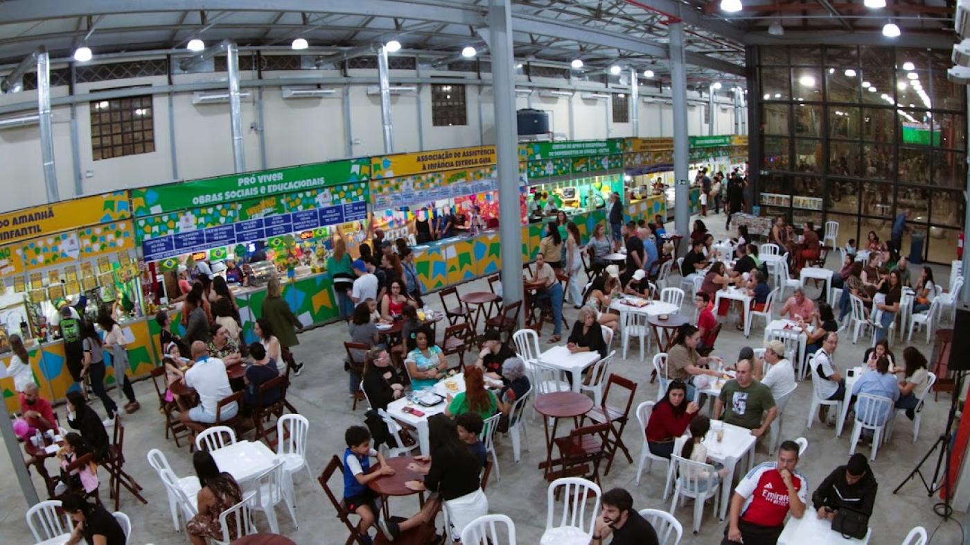 #paratodosverem galpão lotado com pessoas sentadas em cadeiras junto às mesas