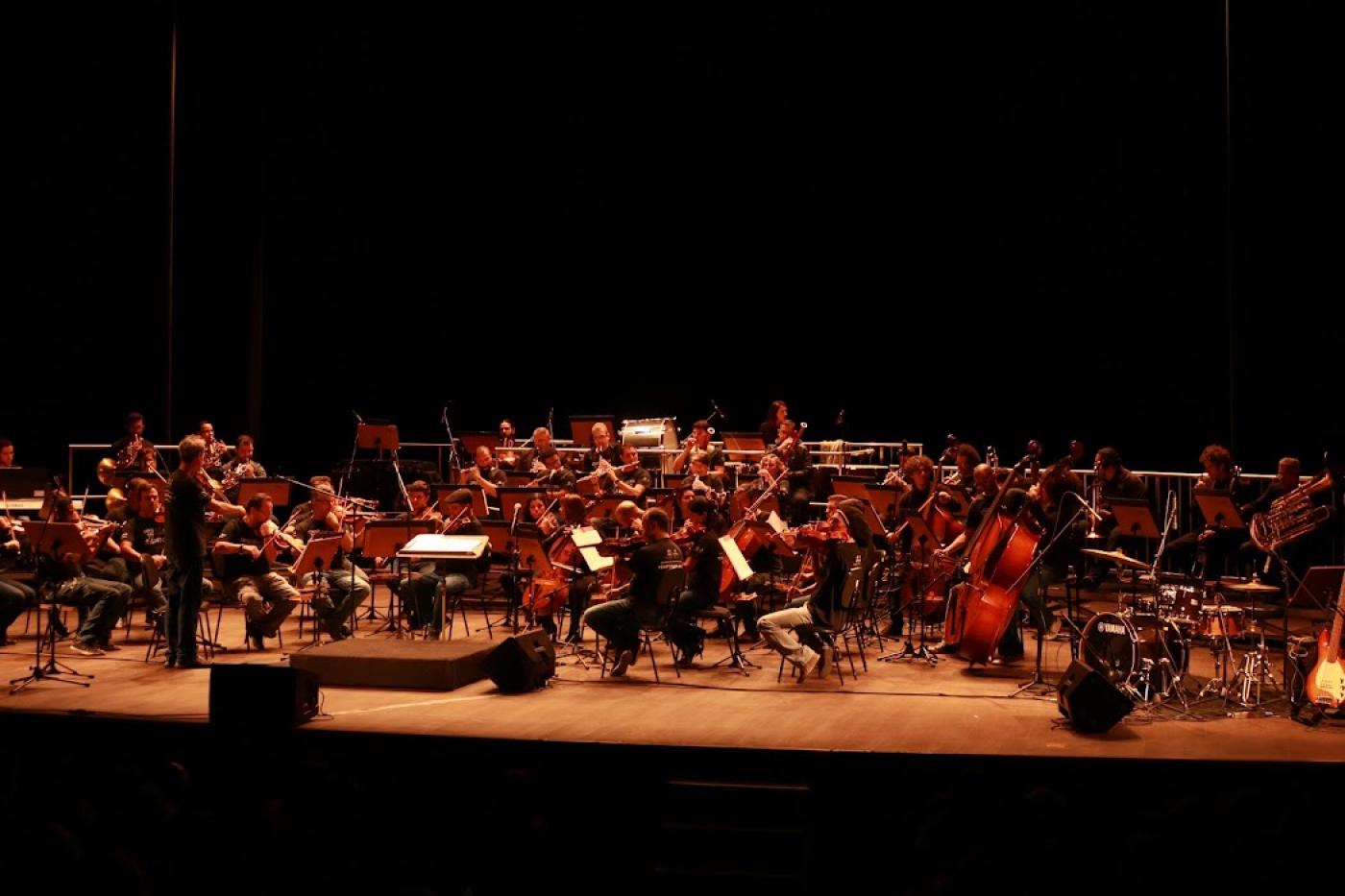 Orquestra se apresentando em um palco. #paratodosverem