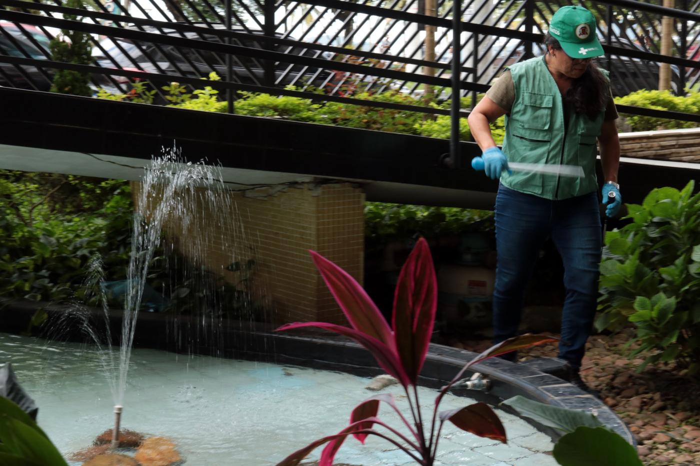 agente uniformizada está ao lado de fonte em condomínio. #paratodosverem