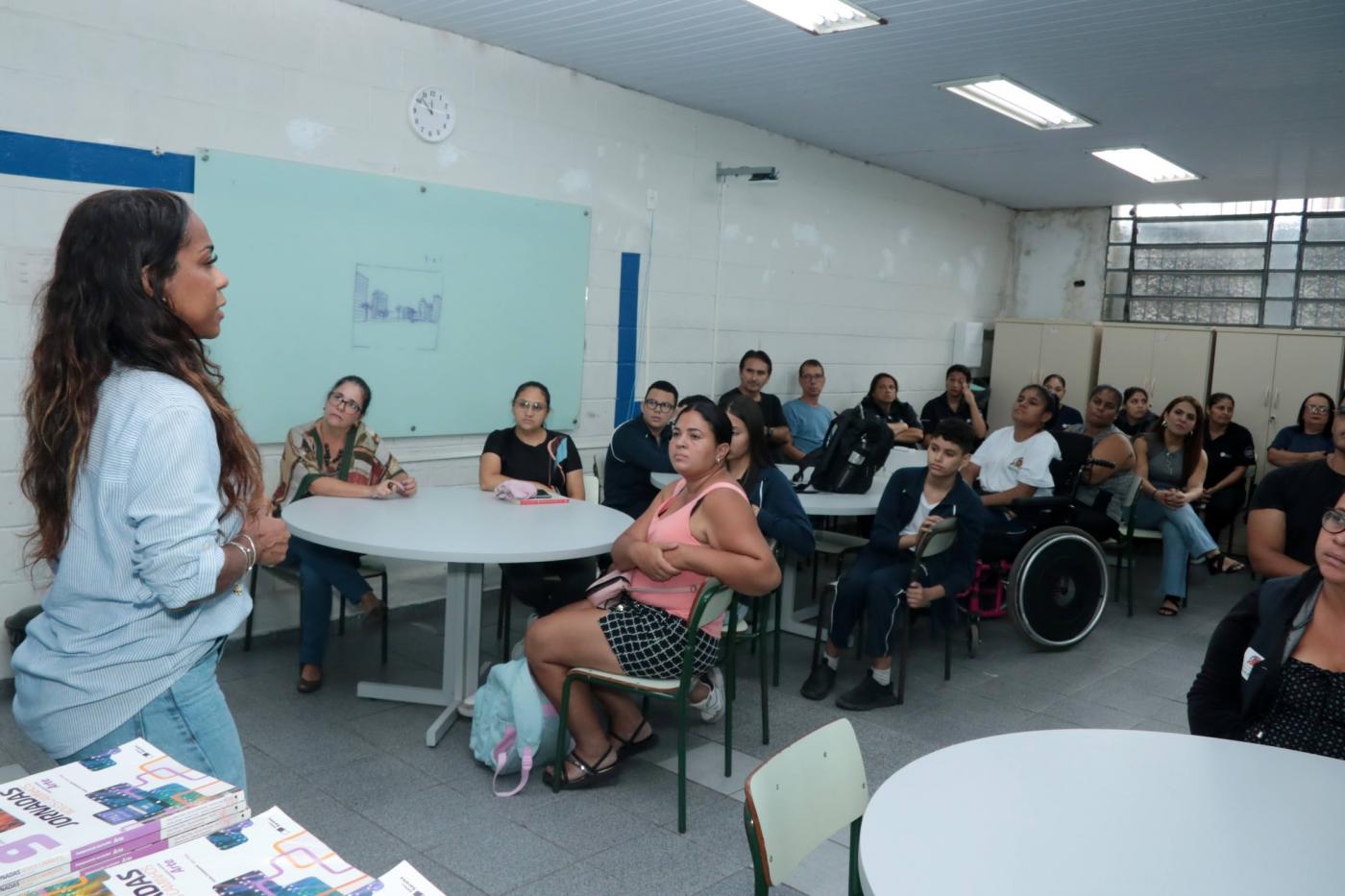 palestra em sala de aula com adultos e alunos sentados. #paratodosverem 