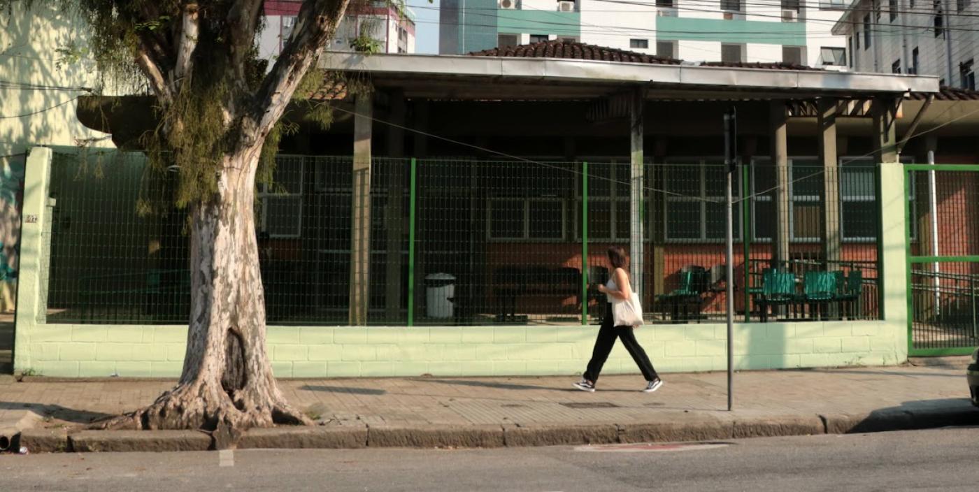 a fachada da unidade com uma árvore na frente uma pessoa andando na calçada. #paratodosverem