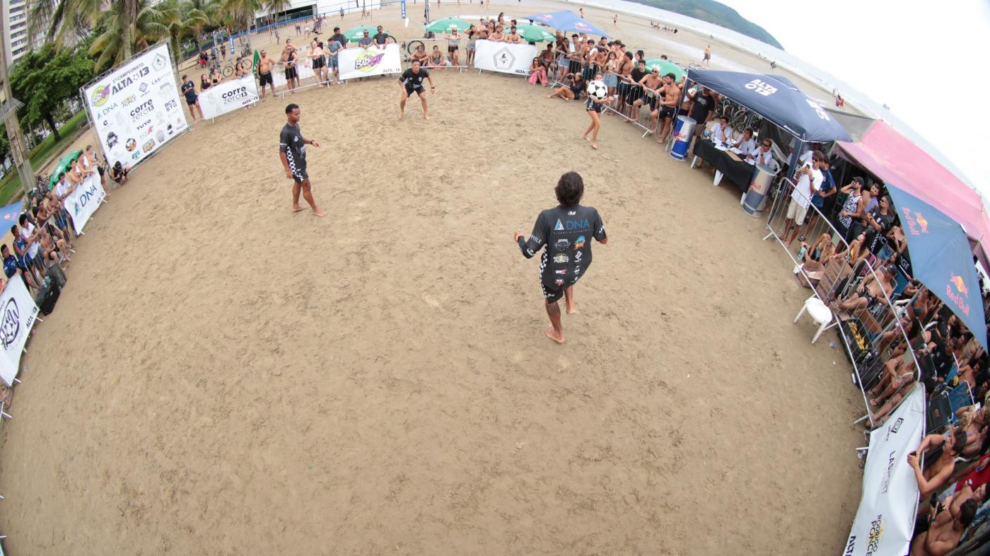 arena na faixa de ariea com grupo de quatro pessoas lançando a bola uma para a outra. #paratodosverem 