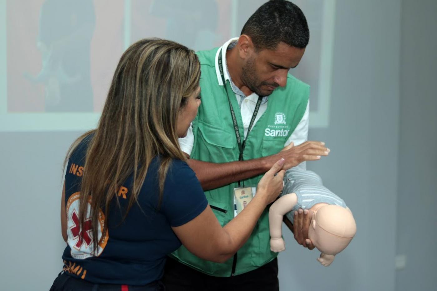 enfermeira ao lado de agente manobrando boneco. #paratodosverem