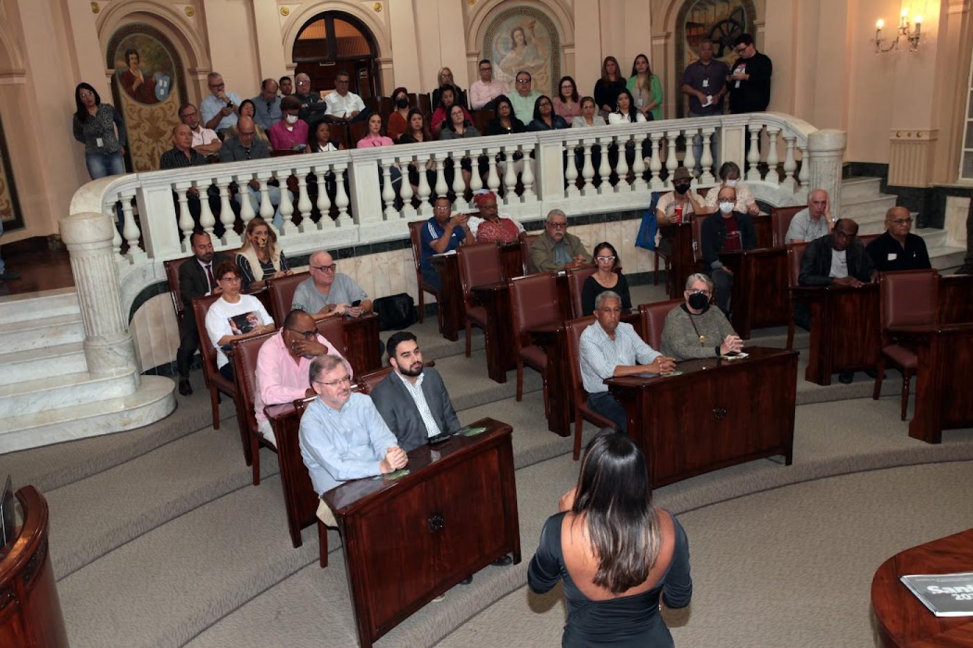 auditório com varias pessoas sentadas ouvindo palestra #paratodosverem