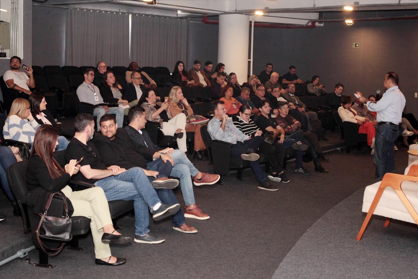 Pessoas no auditório acompanhando o evento #paratodosverem 