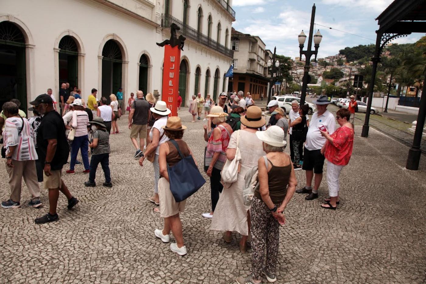 turistas estão na frente de museu pelé. #paratodosverem