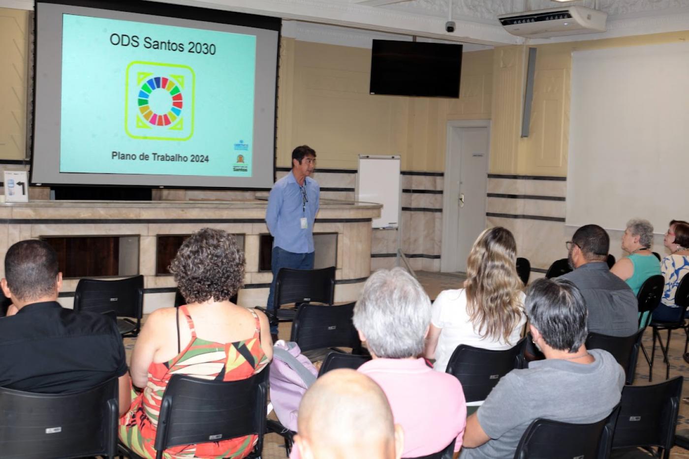 pessoas reunidas com tela tendo o símbolo dos ods 2030