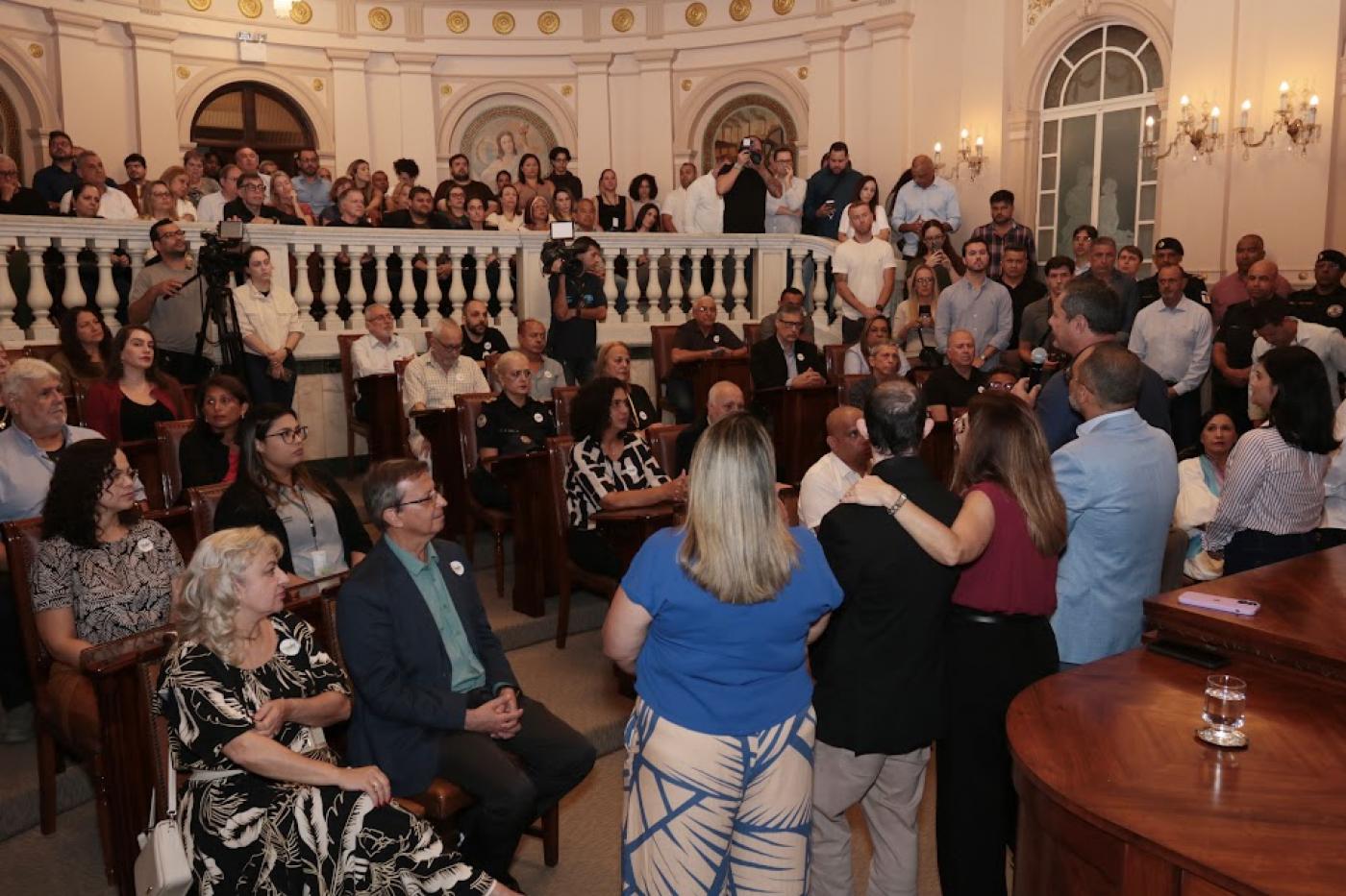sala lotada com pessoas sentadas e em pé #paratodosverem