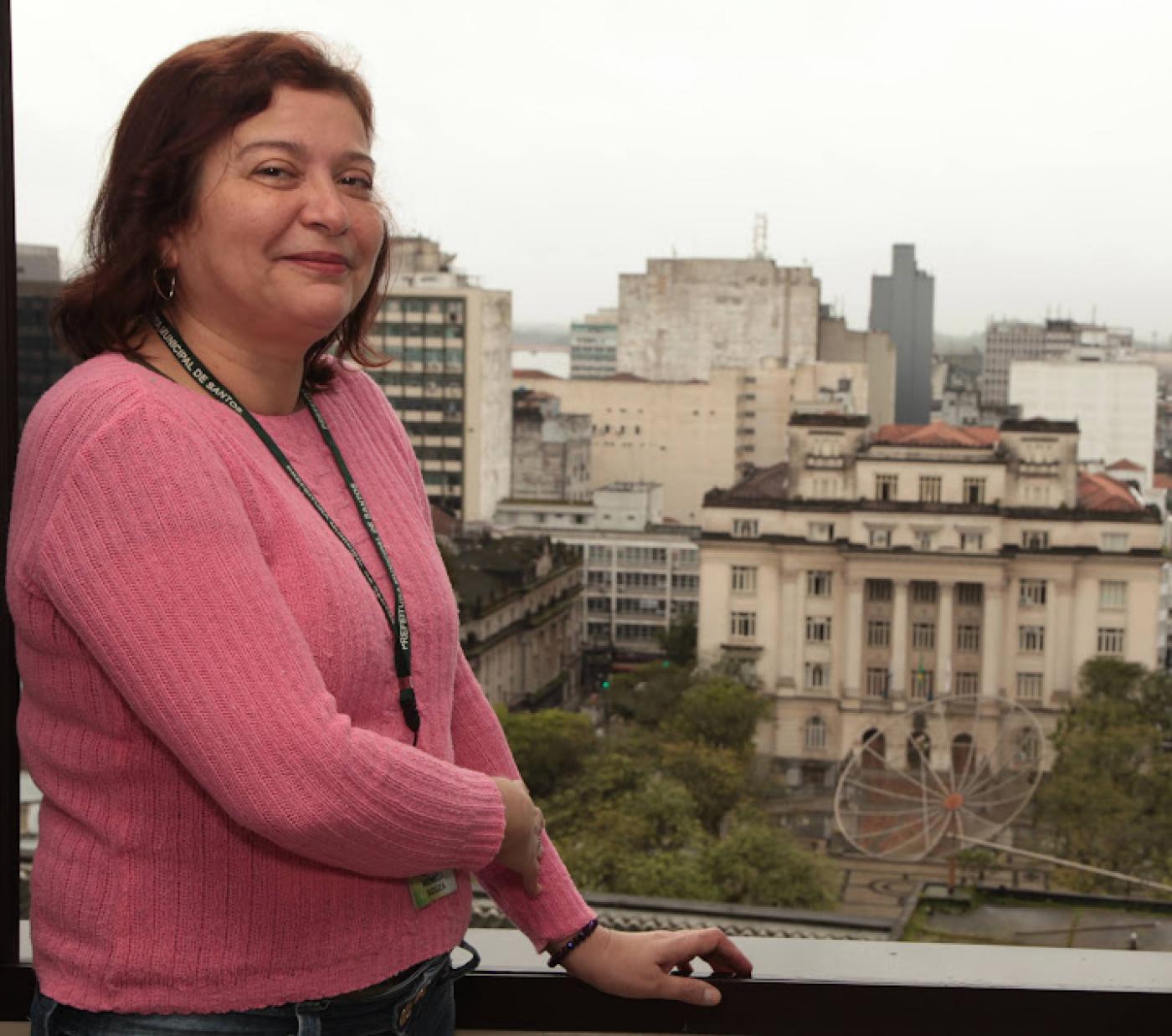 monica posa para foto em uma janela, com o palácio josé bonifácio ao fundo. #paratodosverem