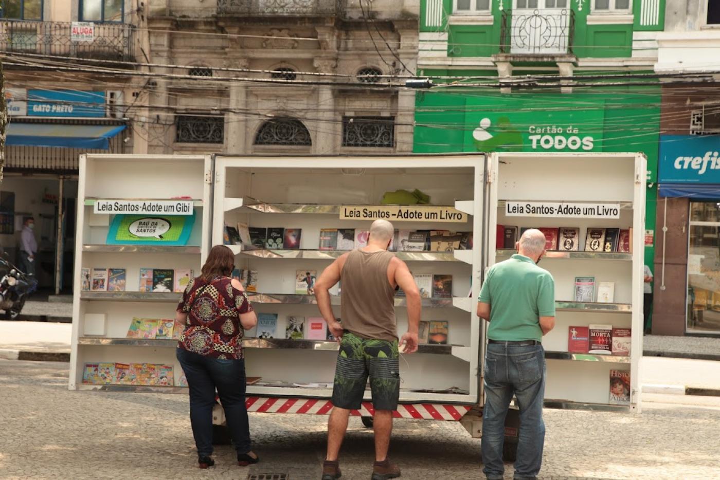 pessoas observam posto móvel do leia santos. #paratodosverem