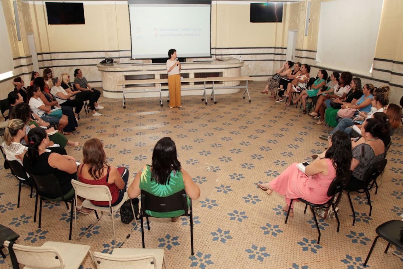 pessoas estão sentadas em candeiras em círculo assistindo a uma palestra. #paratodosverem