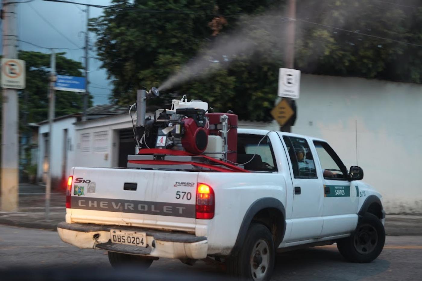 veículo da prefeitura com maquinário na caçamba passa em rua borrifando produto. #paratodosverem