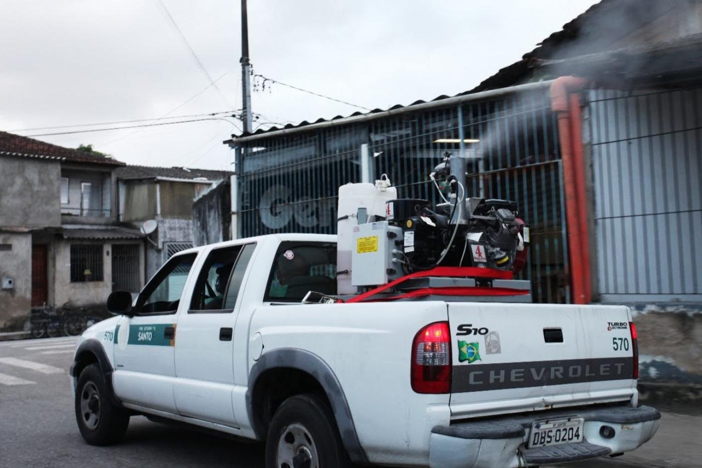 carro com equipamento de dispersão de líquido percorre rua. #paratodosverem