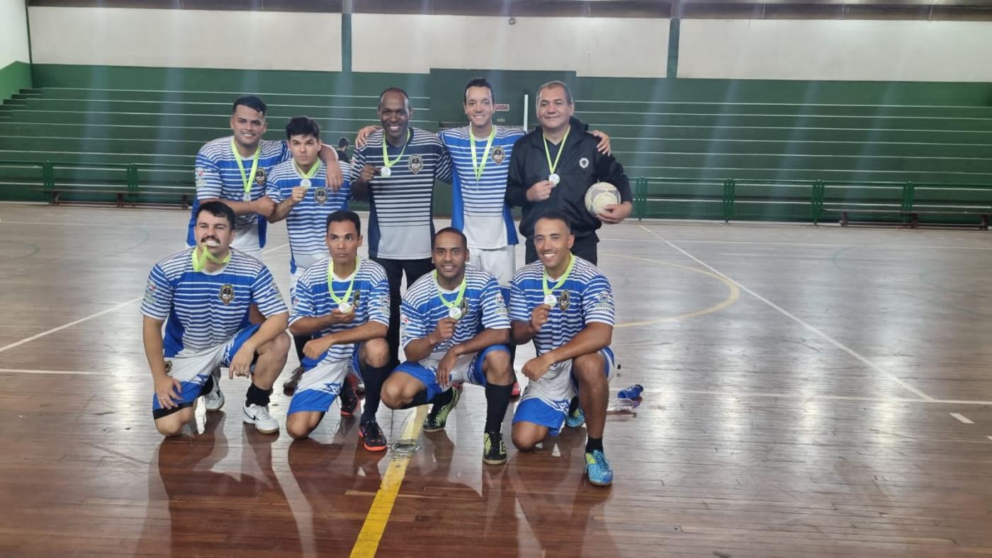 equipe vencedora posa para foto, cada um como a sua respectiva medalha. São 9 pessoas na foto