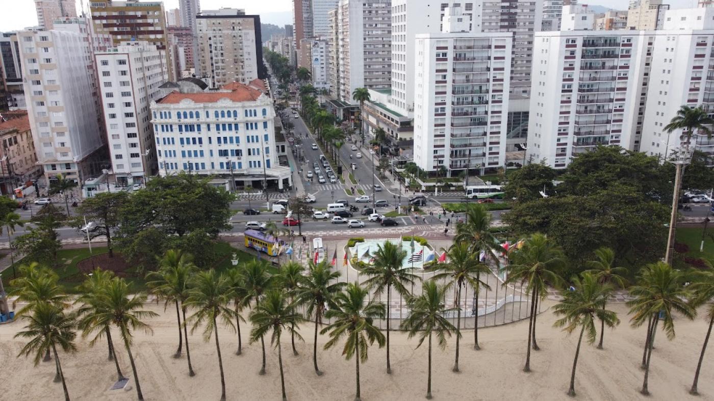 vista aérea do bairro a partir da faixa de areia, de frente para a praça das bandeiras e avenida ana costa. Em primeiro plano se vê as copas verdes das palmeiras e as construções em seguida. #paratodosverem