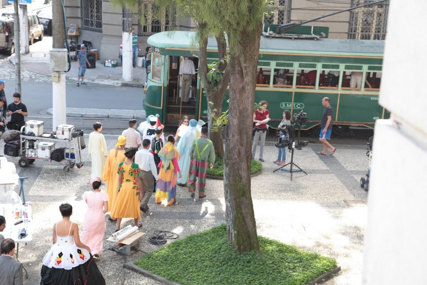 gravação de filme em praça de santos com equipamentos de filmagem e pessoas com roupas de época. bonde compõe o ambiente. #paratodosverem