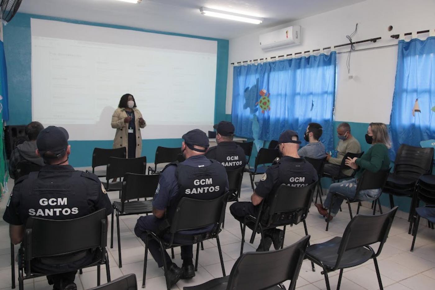 Mulher fala com guardas em sala de aula #paratodosverem