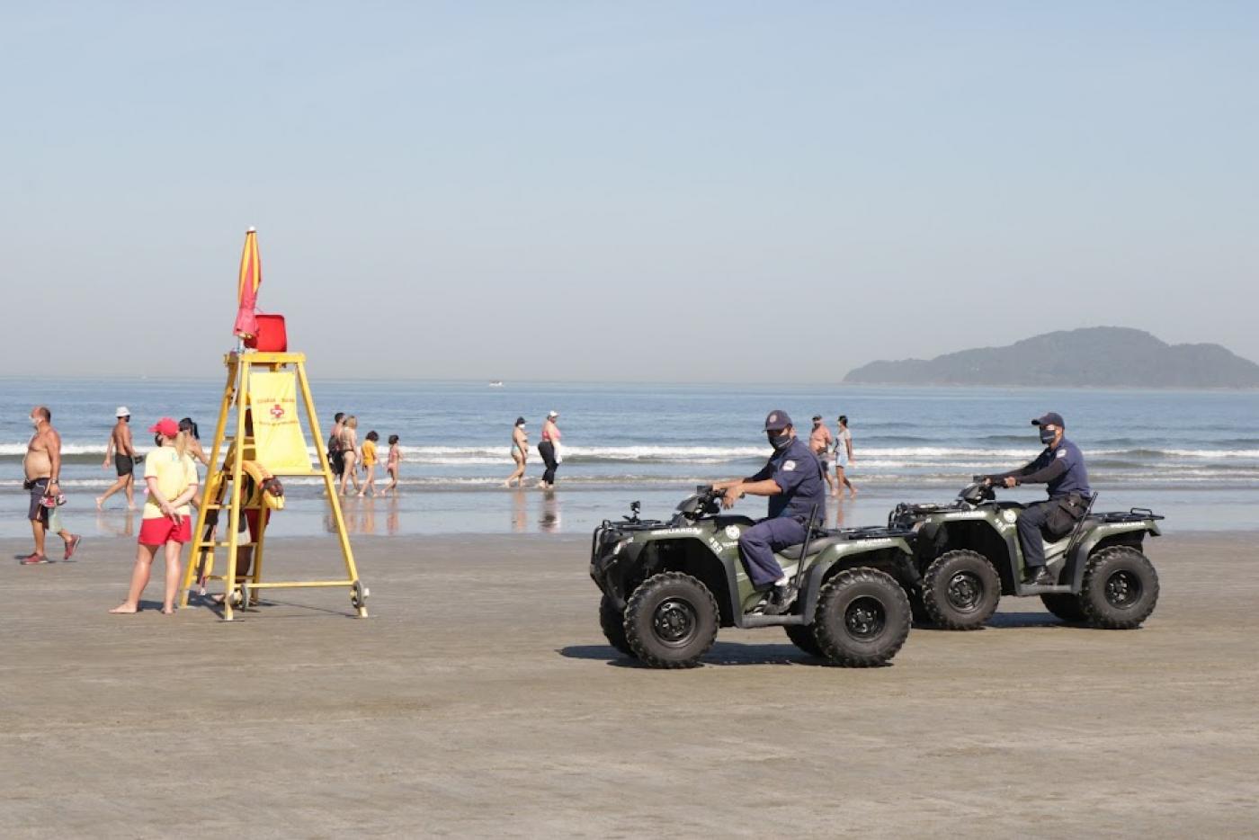 dois quadriciciclos são pilotados por guardas muncipais na faixa de areia da praia próximo à água. #paratodosverem