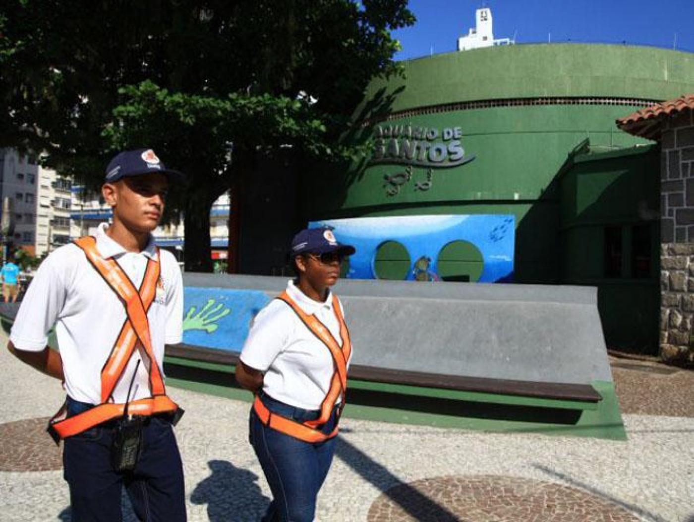 dois jovens usando uniforme, com bone e colete reflexivo. #paratodosverem 