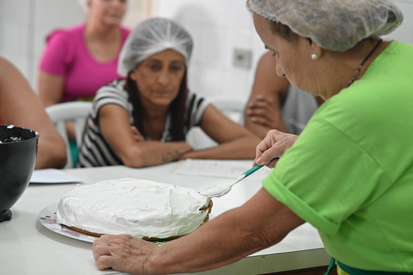 aluna está atenta à professora decorando bolo. #paratodosverem