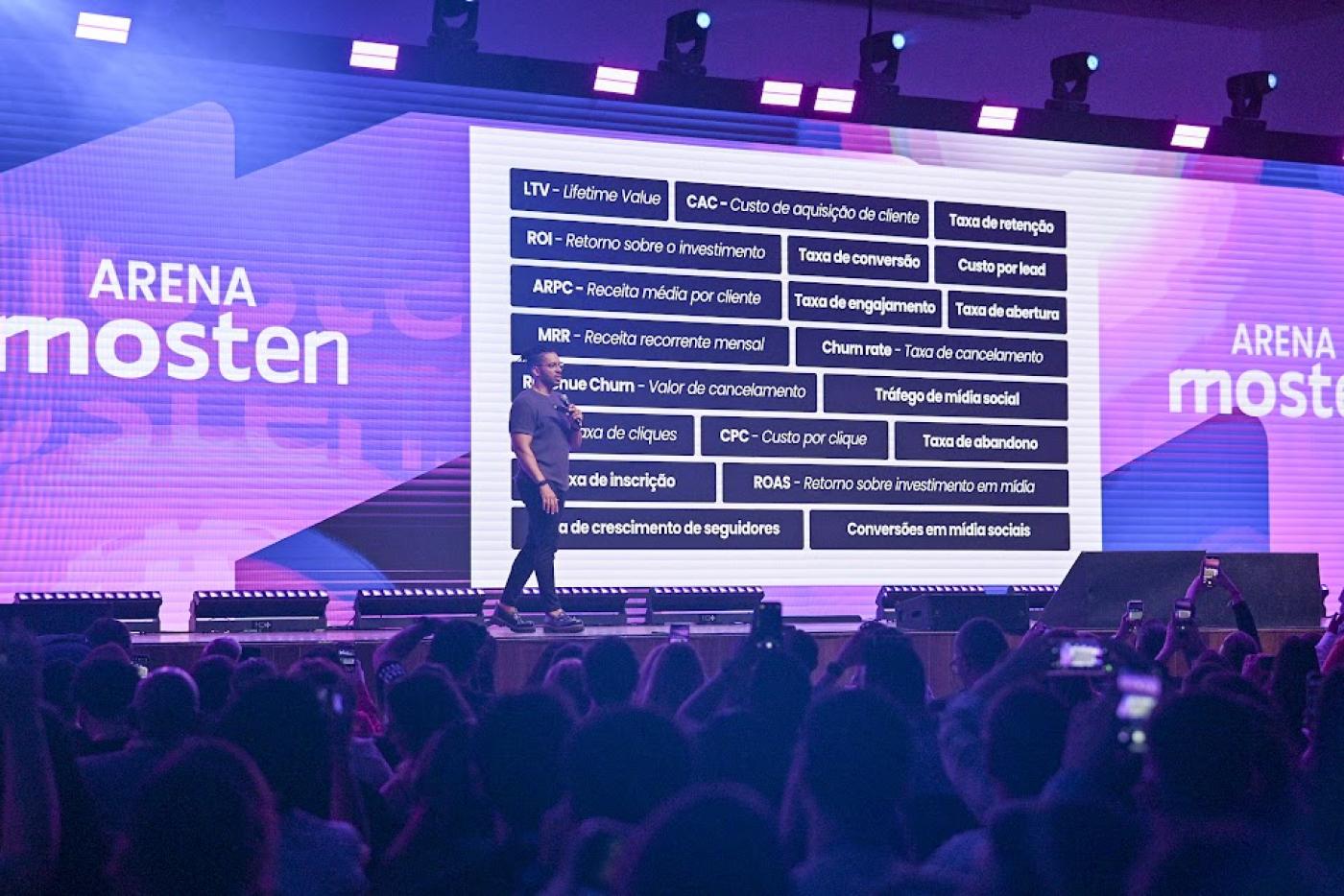 pessoa em pé com telão ao fundo #paratodosverem