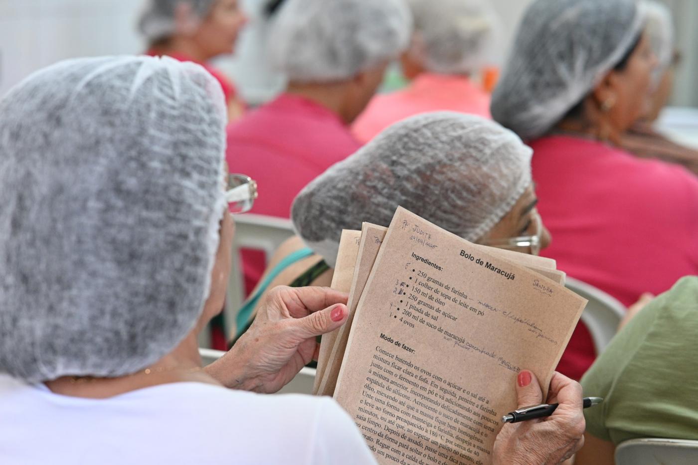 mulher está de costas segurando papel com receita de bolo. #paratodosverem