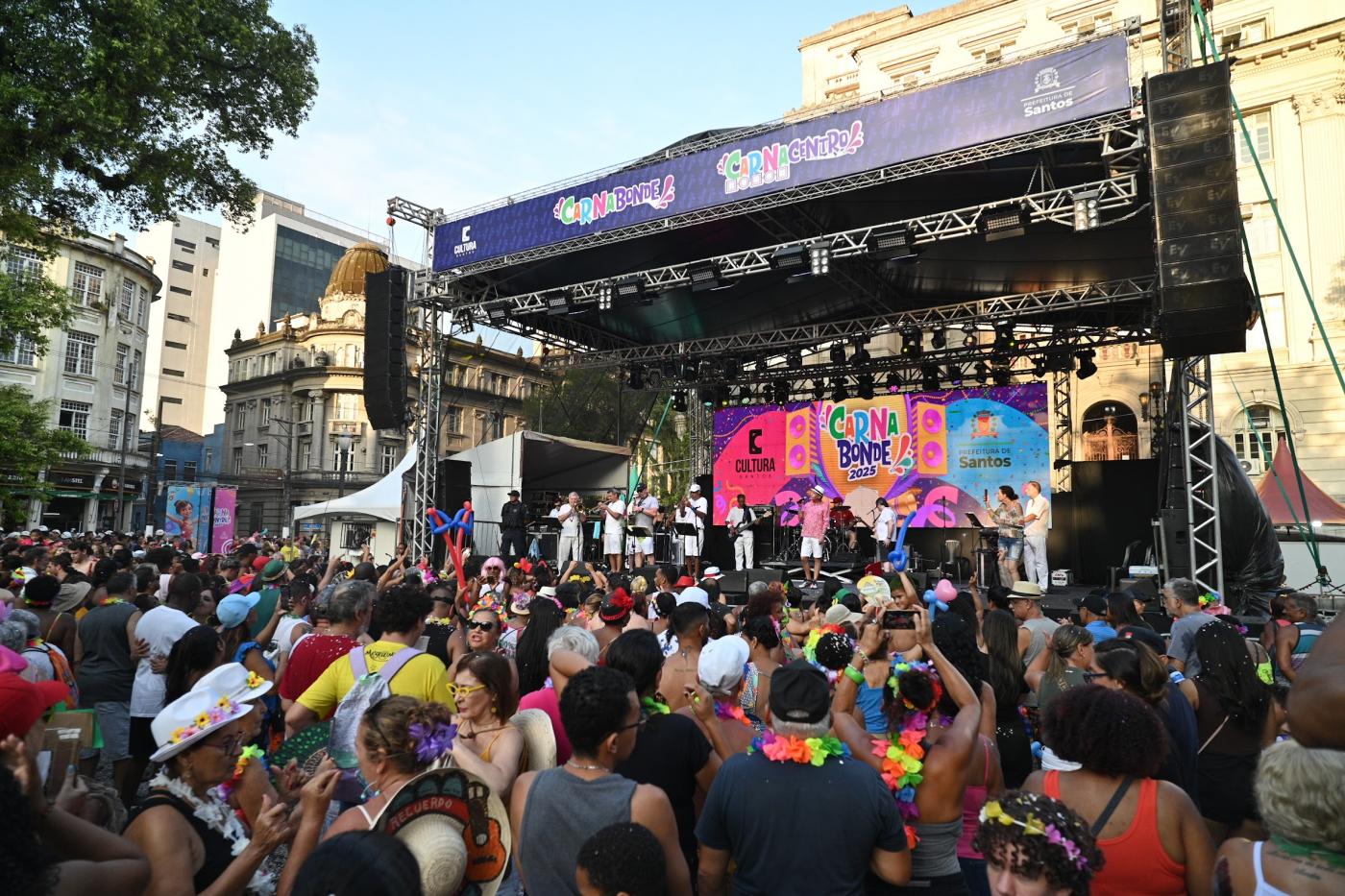 público lota praça. Palco com show ao fundo. #paratodosverem