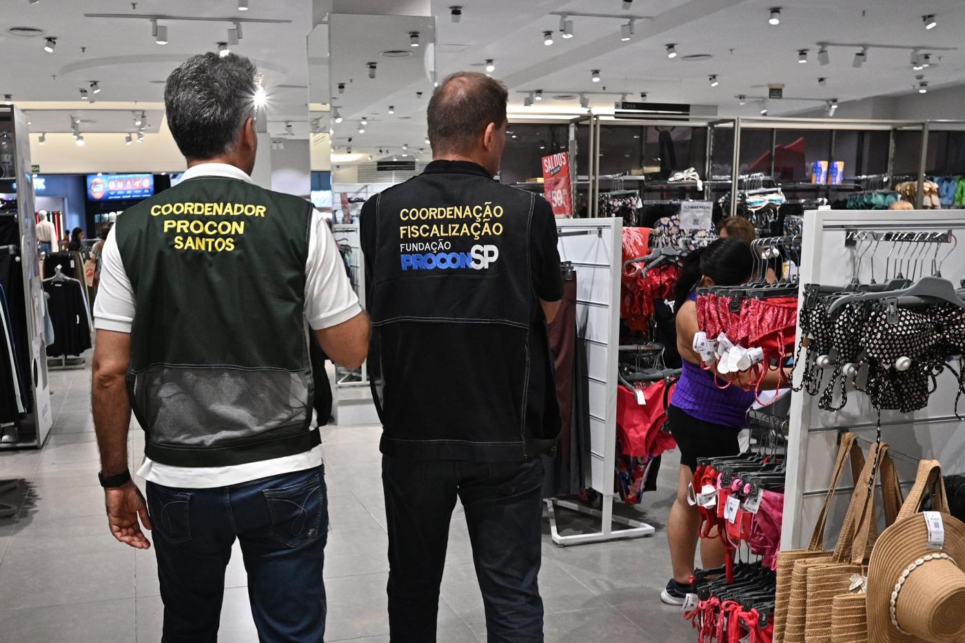 fiscais com coletes de identificação dentro de loja. #paratodosverem 