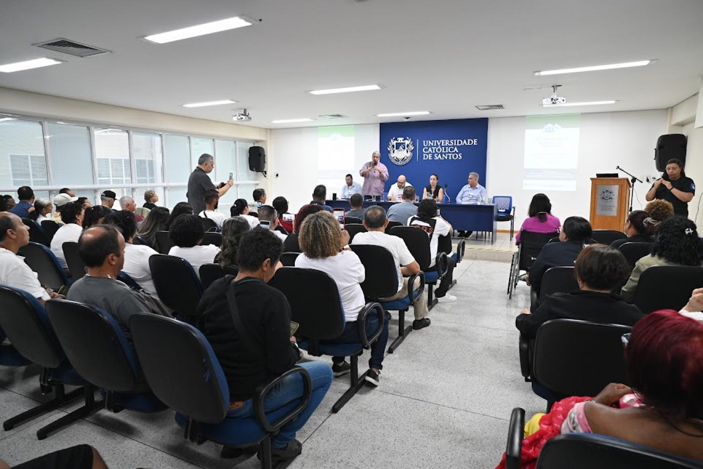 pessoas sentadas em um auditório #paratodosverem