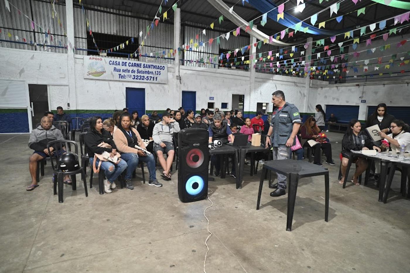 pessoas estão sentadas em salão assistindo palestra. #paratodosverem