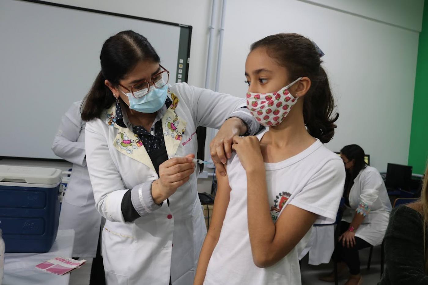 mulher vestindo avental branco e usando máscara vacina menina que usa máscara. #paratodosverem