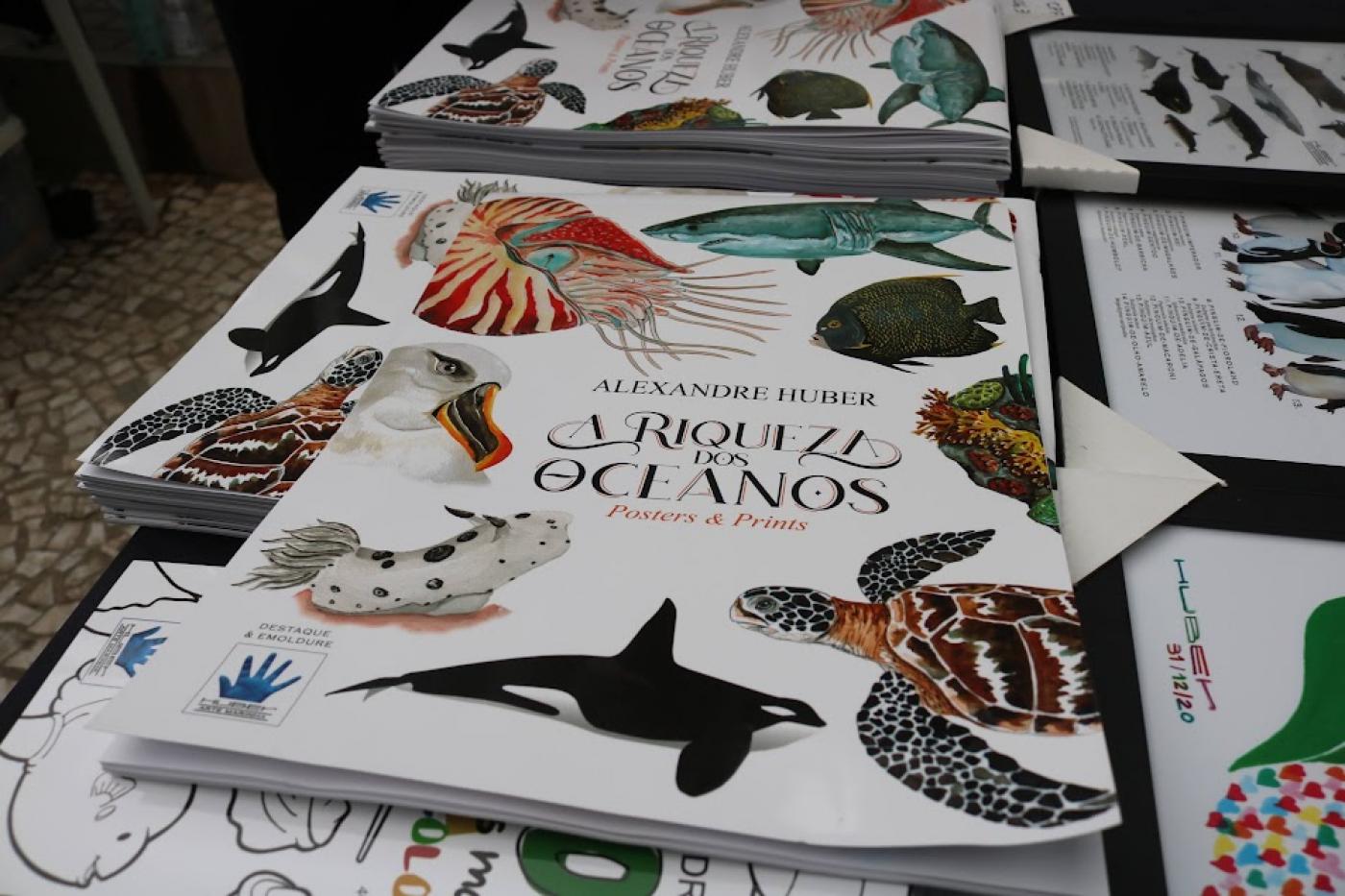 livros com arte sobre animais marinhos colocados sobre uma mesa. #paratodosverem