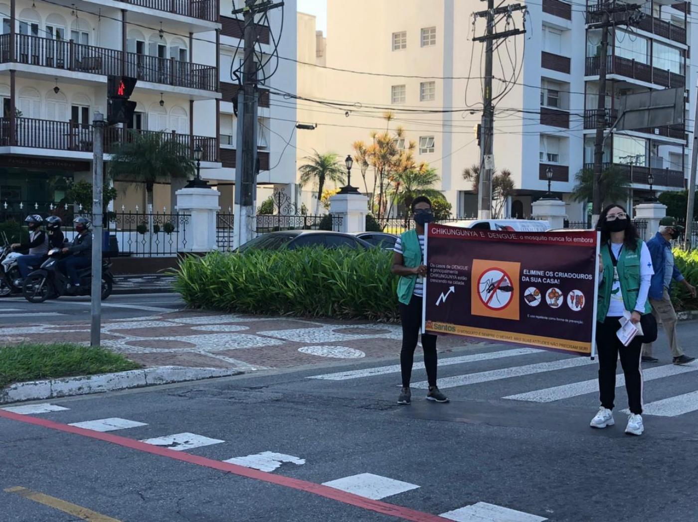duas pessoas estão segurando faixa no centro de avenida. #paratodosverem