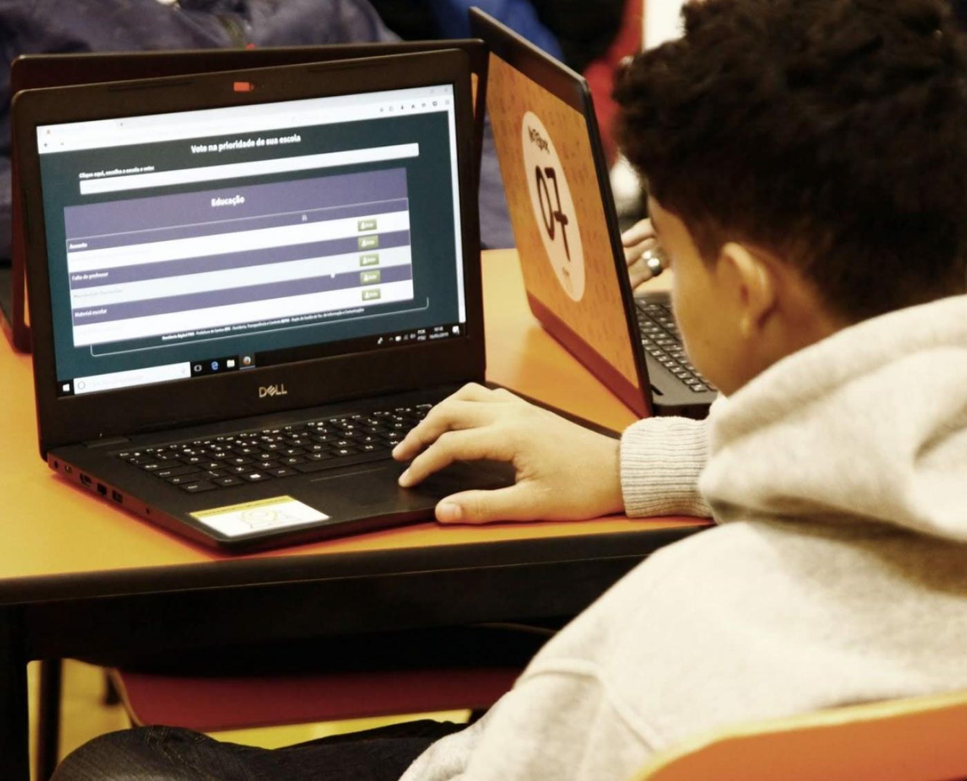 Jovem está digitando o teclado de um laptop. #Paratodosverem