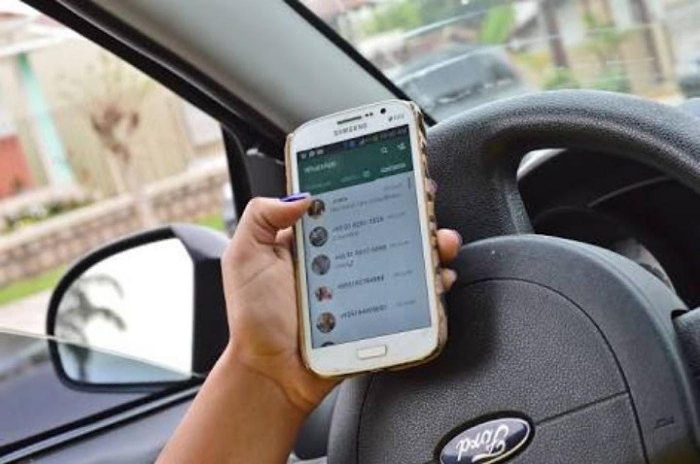 Mão está com celular ao volante #pracegover 