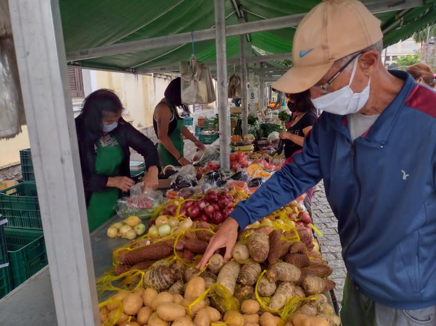 homem mexe em batatas em bancada com vários orgânicos #paratodosverem