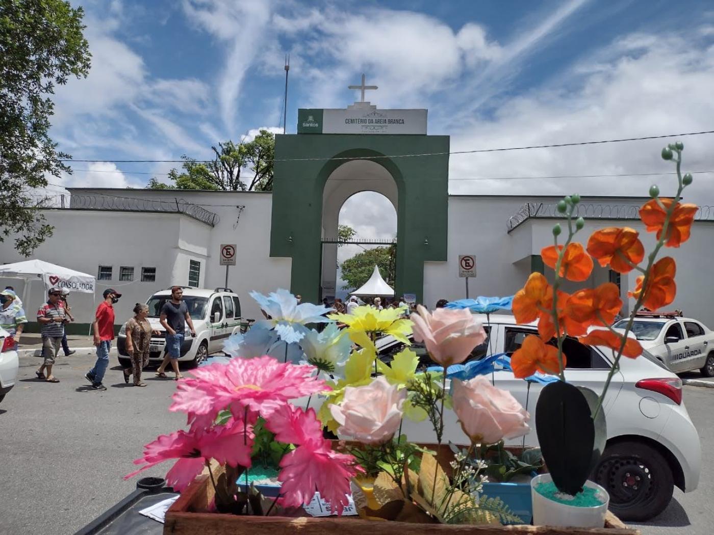 fachada de cemitério com vasos de plantas de plástico em primeiro plano. #paratodosverem