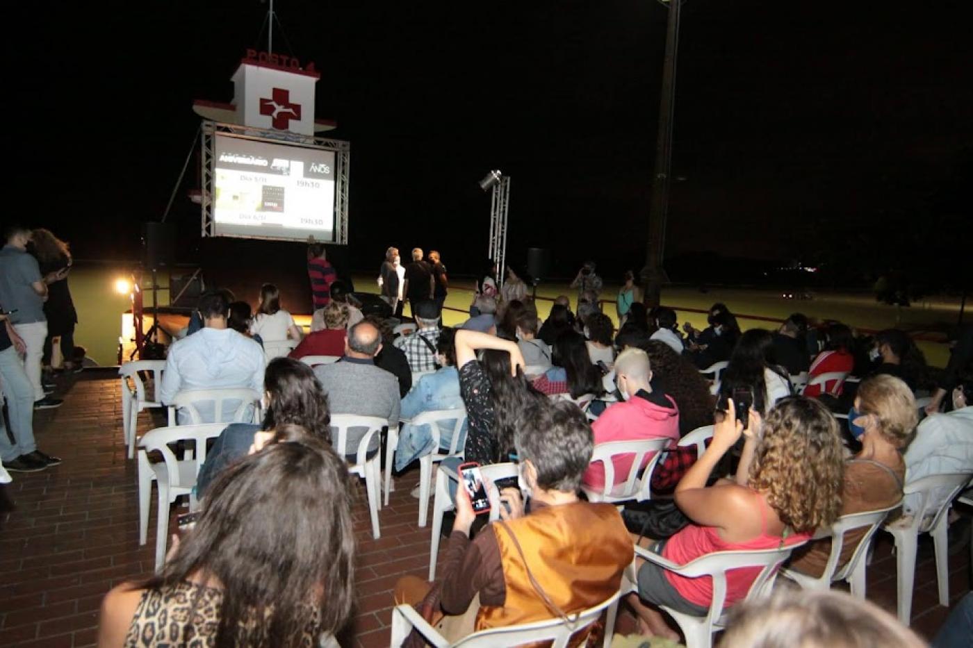 pessoas assistem à exibição no terraço do cinema #paratodosverem