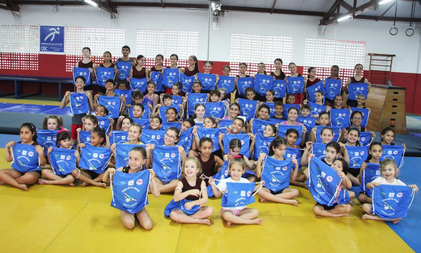crianças posam para foto segurando novas mochilas. #paratodosverem 