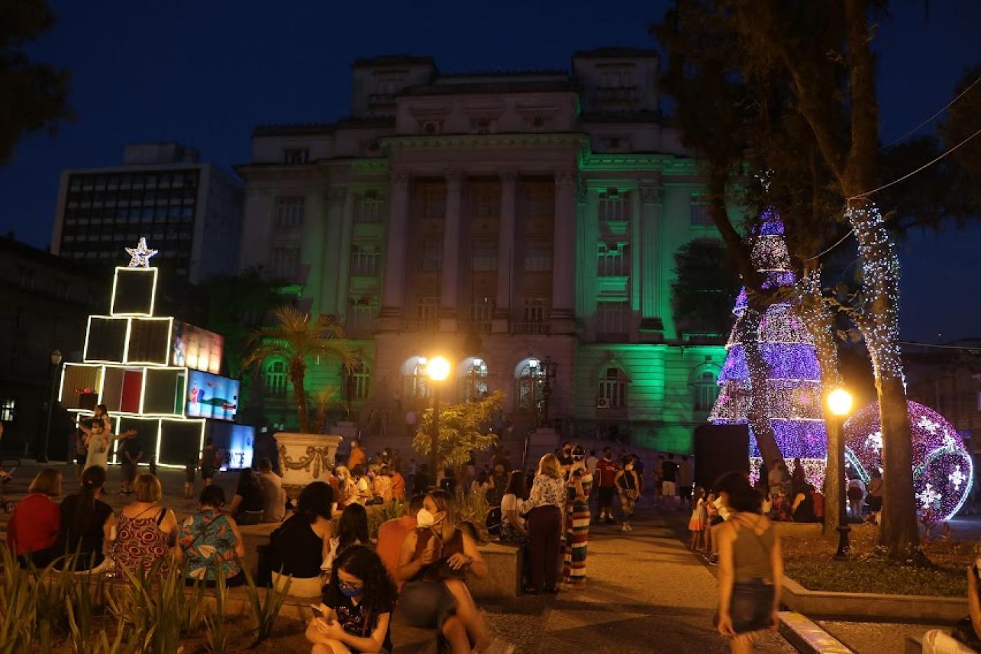 pessoas na praça e arvores iluminadas #paratodosverem