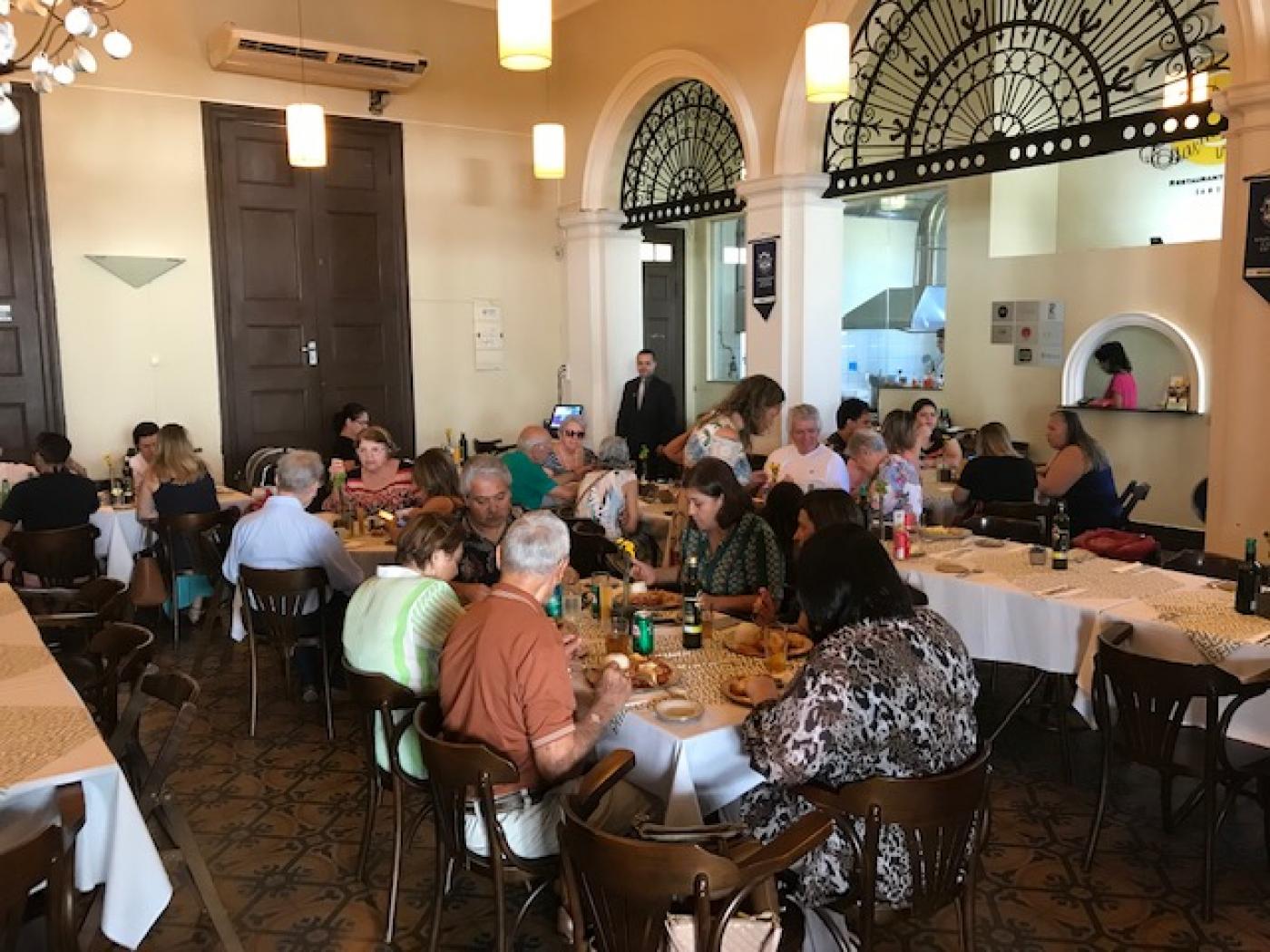 Cerca de 20 pessoa salmoçam em mesas do restaurante Estação Bistrô