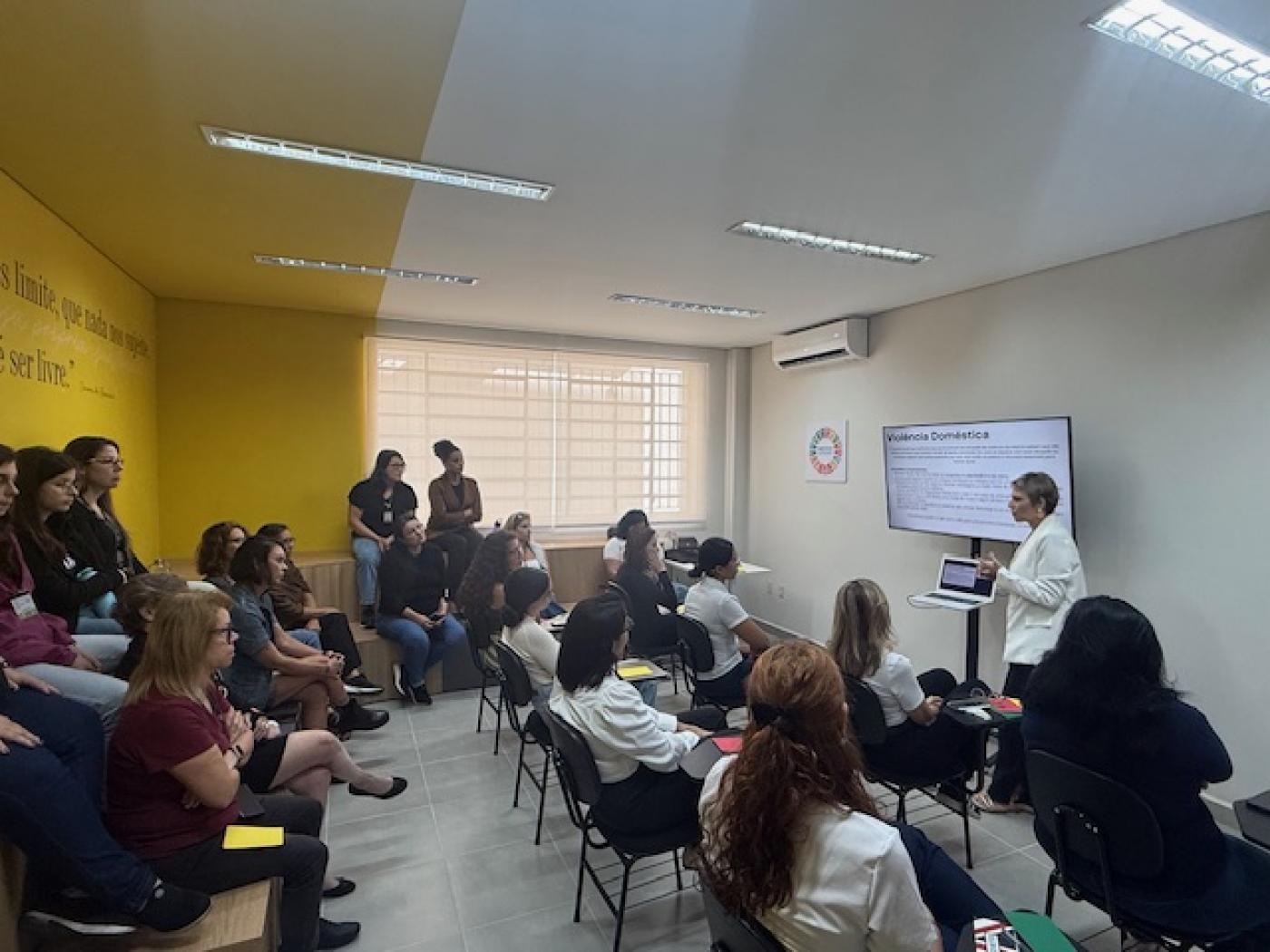 mulheres sentadas em auditório assistem palestra. #paratodosverem