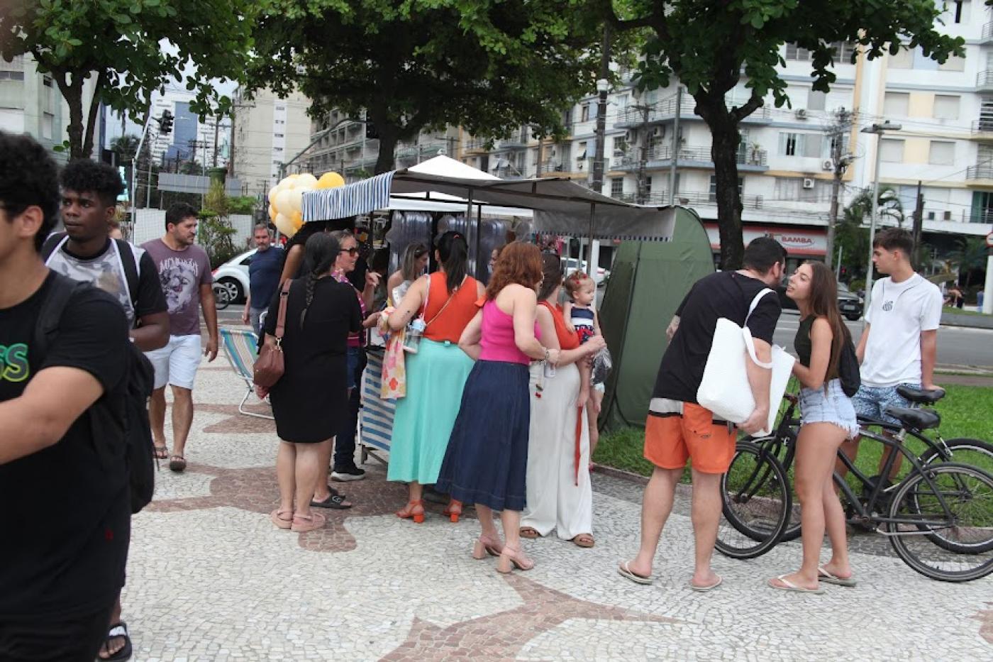 pessoas olhando produtos em barraca #paratodosverem